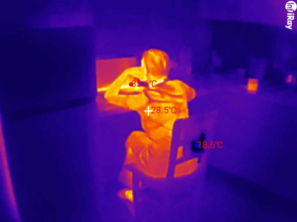 Thermal image of a person showing temperature differences between exposed skin, clothing and the surrounding room.