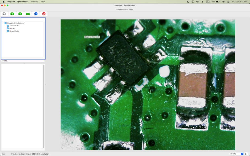 Close-up microscope view of an eight-pin SMD integrated circuit, solder joints and ceramic capacitors on a PCB.